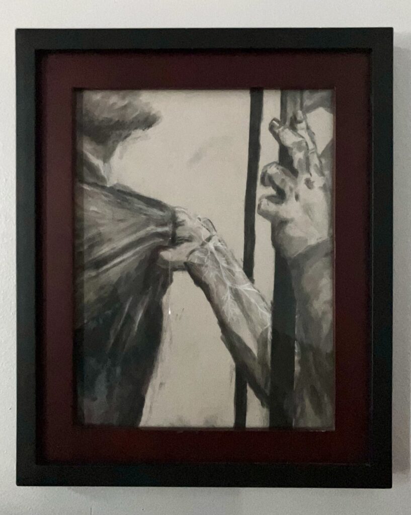 A framed charcoal drawing of two people, one of whom is grabbing the other by the shirt and pulling him closer. Their faces aren't visible.