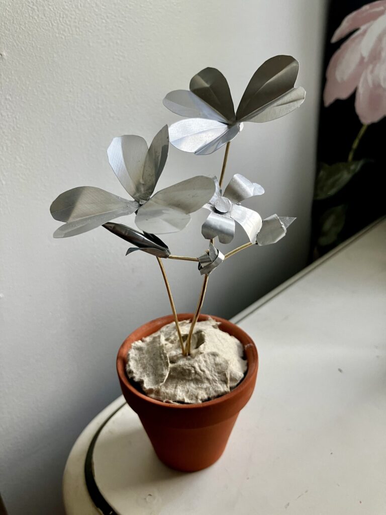 A sculpted wood sorrel made of cut soda cans.