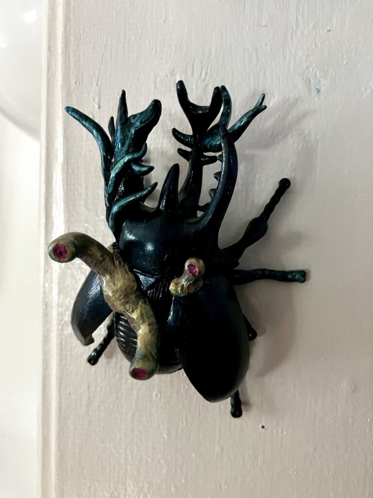 A photo of a sculpted beetle with strange, alien tendril growths.
