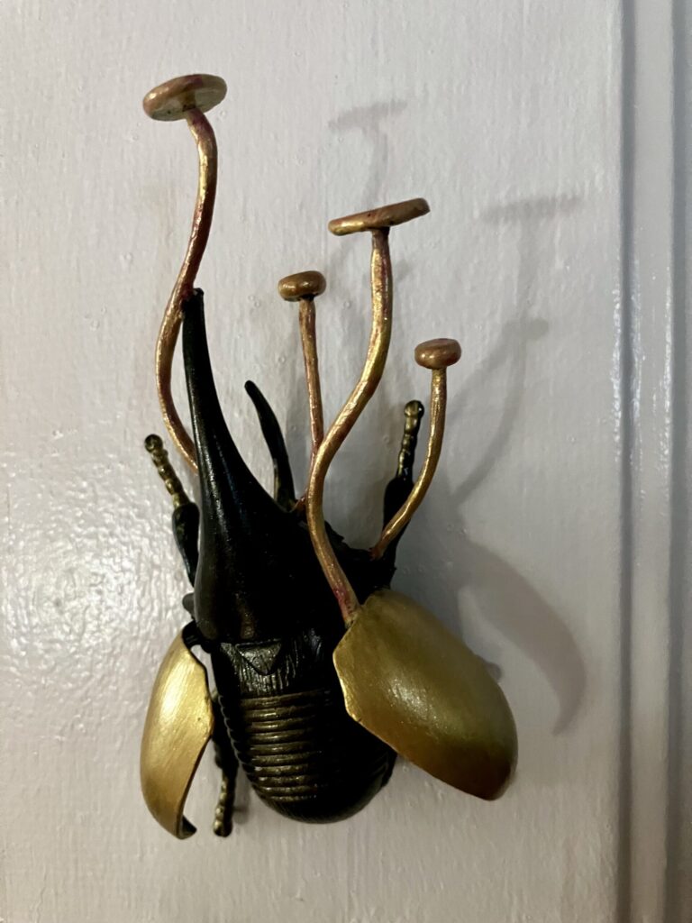 A photo of a sculpted beetle with delicate mushrooms growing from it.