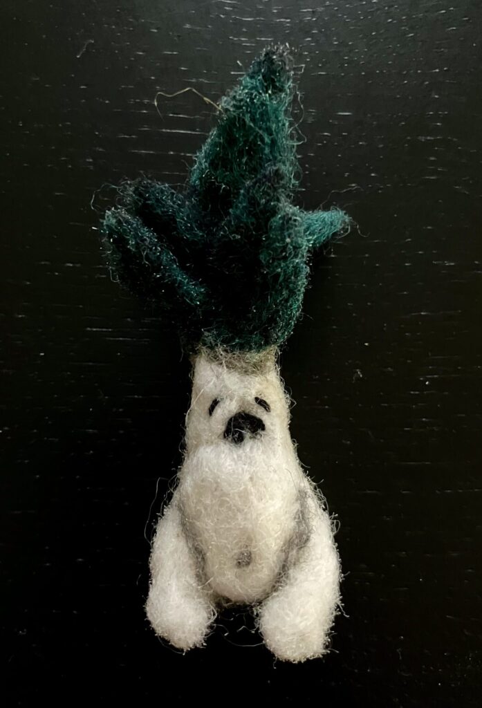 A needlefelted mandrake sitting.