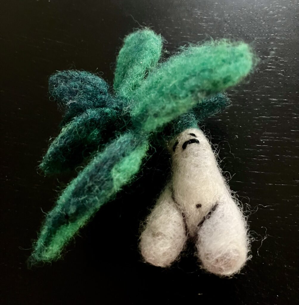 A needlefelted mandrake with leaves too large for it to support.