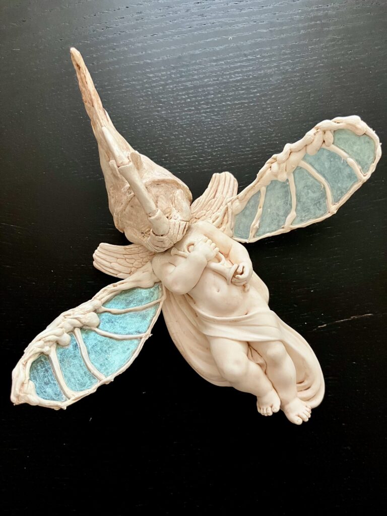 A cherub statue that has been given a beetle head and wings.