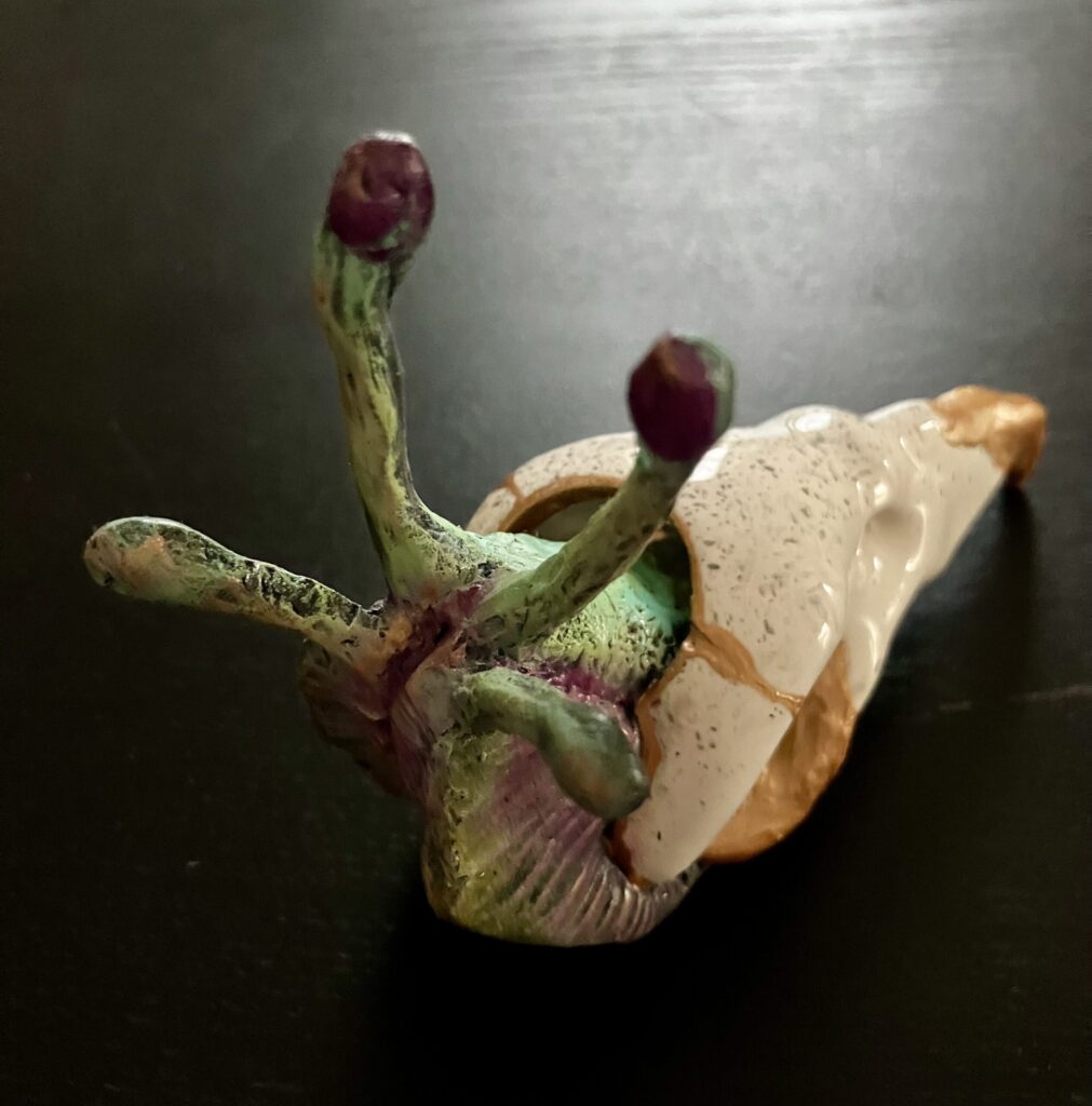 A sculpted snail with a bird skull for a shell.
