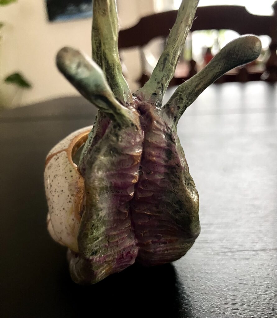 A sculpted snail with a bird skull for a shell.