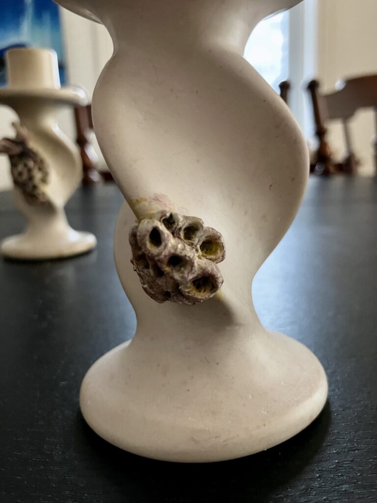 A candlestick with a sculpted wasp nest on it.