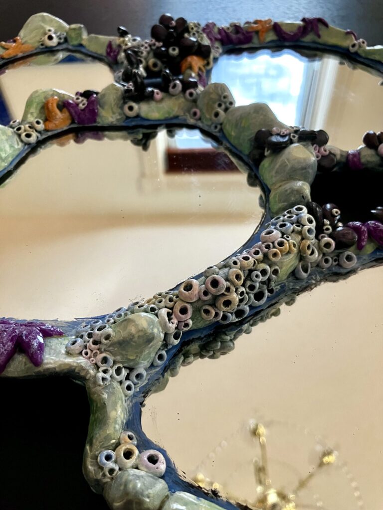 An assemblage of mirrors with tidepool rocks and creatures sculpted around them.