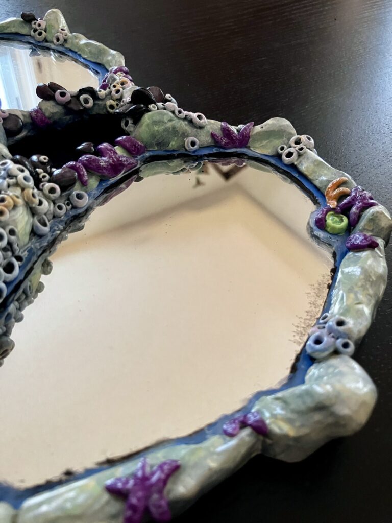 An assemblage of mirrors with tidepool rocks and creatures sculpted around them.