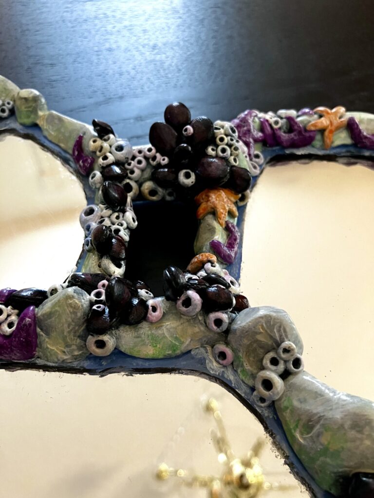 An assemblage of mirrors with tidepool rocks and creatures sculpted around them.
