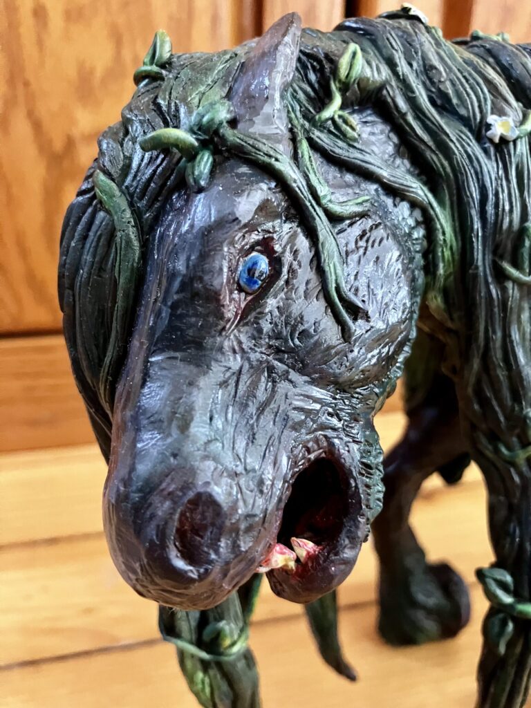 A close up of a sculpted each-usige with teeth bared.